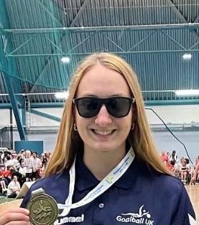 Person smiling at camera holding a medal