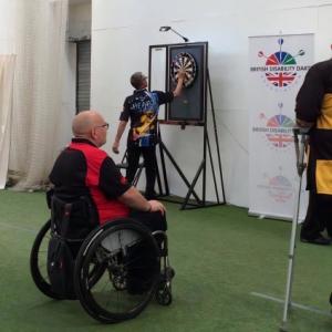 members from local darts league practice shooting darts on the dart board.